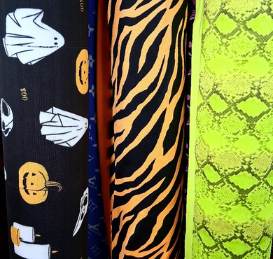 Four fabric swatches with Halloween-themed patterns including ghosts, pumpkins, and a snake skin pattern.[designerspandexandmore.com]